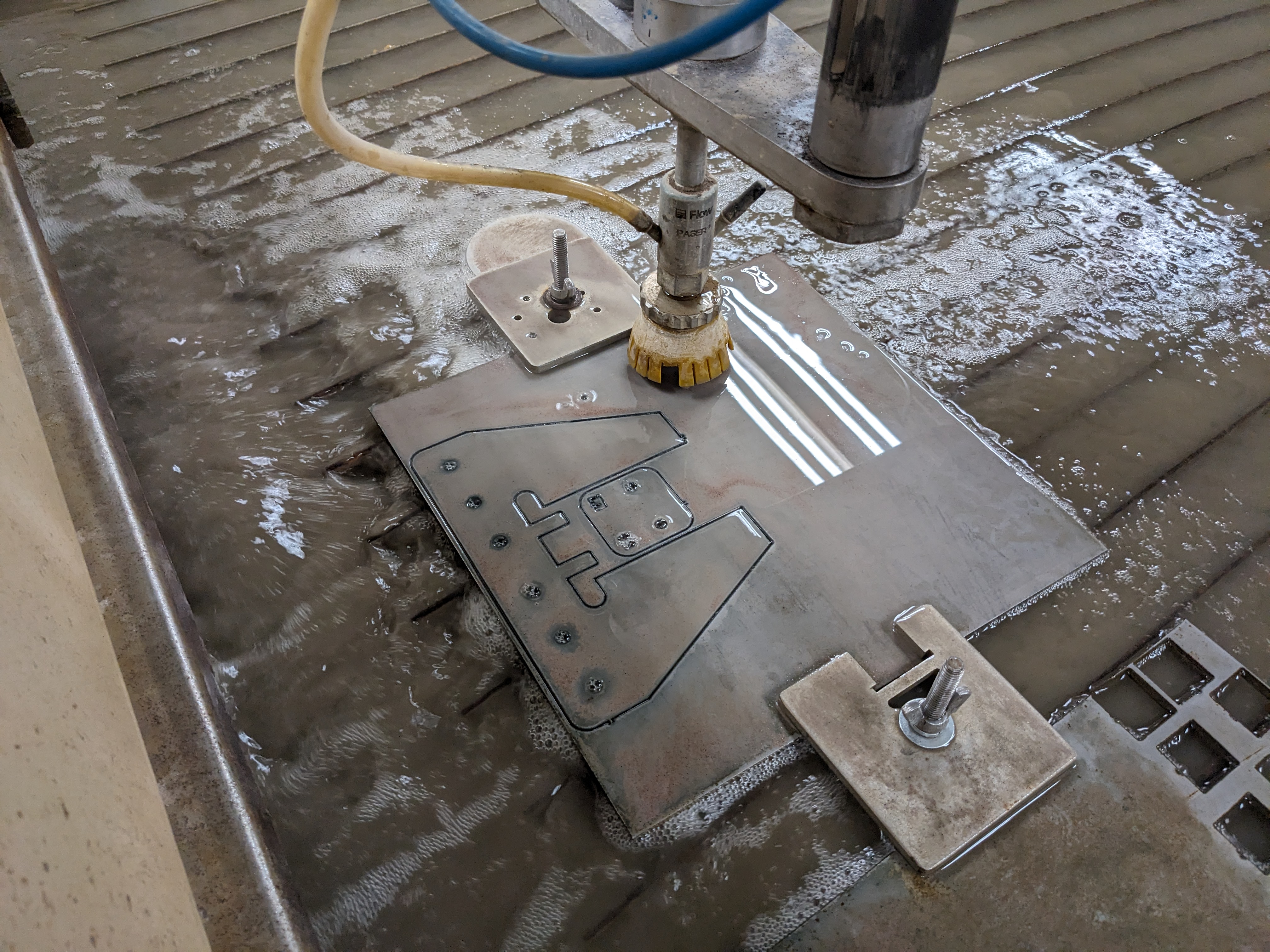 Looking down into a large waterjet as it cuts through a steel plate